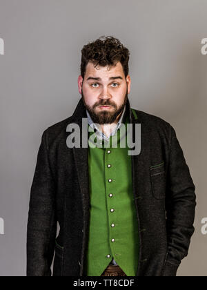 Cool Mann mit Tracht posiert vor grauem Hintergrund Stockfoto