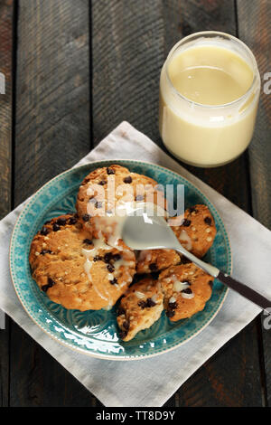 Cookies auf Platte mit Jar von Kondensmilch auf hölzernen Hintergrund Stockfoto