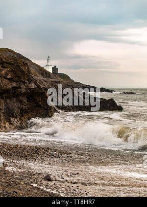 Leuchtturm auf mumbles Mumbles Head als von Armband Bucht mit Wellen auf den Strand gesehen. Swansea, Gower, Wales, UK. Stockfoto