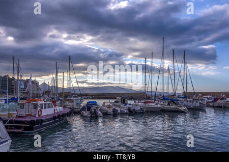 Heraklion, Kreta - Griechenland. Blick auf den alten venezianischen Hafen von Heraklion Stadt voller Fischerboote und Yachten. Bewölkter Himmel Stockfoto