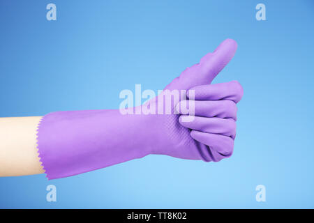 Gummihandschuh an Hand, auf blauem Hintergrund Stockfoto