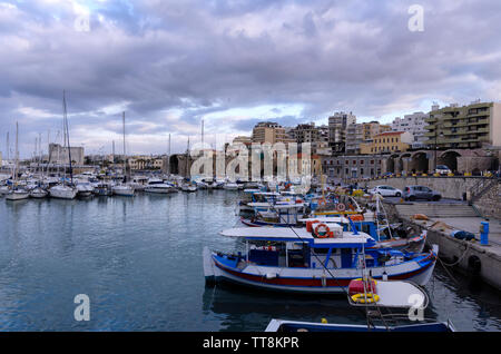 Heraklion, Kreta - Griechenland. Blick auf den alten Venezianischen Hafen mit den traditionellen Fischerbooten und die Stadt Heraklion mit der alten venezianischen Werften Stockfoto