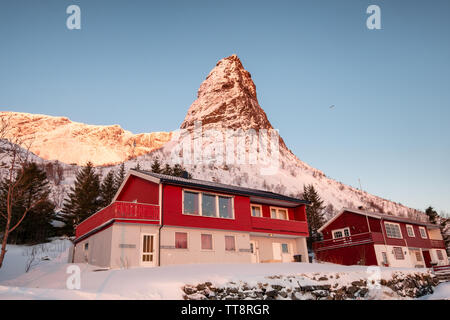 Sonnenaufgang auf dem verschneiten Berg mit skandinavischen Dorf in Morgen im Lofoten Inseln, Norwegen Stockfoto