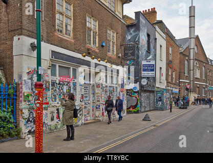 LONDON ENGLAND BRICK LANE PERSON FOTOGRAFIEREN WANDGEMÄLDE ODER GRAFFITI AN DEN WÄNDEN EINES SHOP VORNE Stockfoto