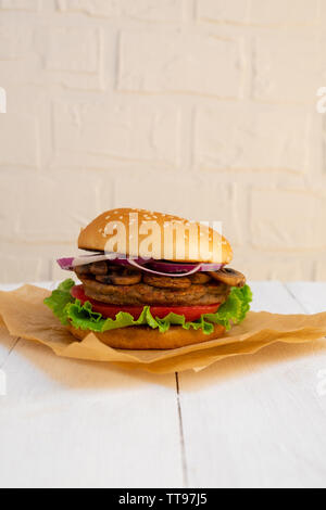 Vegane Burger mit Bohnen und Pilzen auf weißem Holz- Hintergrund. Stockfoto