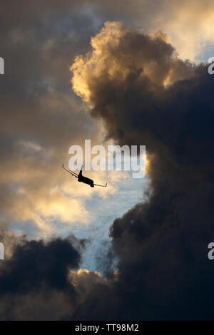 Sonnenuntergang cloudscape, grauen Wolken und Farben aus der Sonne, die sich unter dem Horizont befindet. Plus ein Verkehrsflugzeug, Abfahrt Flughafen Stansted Essex Stockfoto