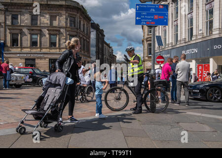 Paisley, Schottland, Großbritannien. 15 Juni, 2019. Ein junger Junge trifft ein Offizier aus Polizei Schottland auf einem Fahrrad an Paisley Carfest 2019 In diesem Jahr feiert er den 6-jähriges Jubiläum. Gezeigt werden eine Reihe von klassischen Fahrzeugen, Oldtimer, Spezialist kundenspezifische Autos, Muscle Cars, supercars und Einsatzfahrzeuge. Alle Spendengelder gehen an dem Tag, an dem St. Vincent's Hospiz in Howwood zu unterstützen. Credit: Skully/Alamy leben Nachrichten Stockfoto