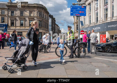 Paisley, Schottland, Großbritannien. 15 Juni, 2019. Ein junger Junge trifft ein Offizier aus Polizei Schottland auf einem Fahrrad an Paisley Carfest 2019 In diesem Jahr feiert er den 6-jähriges Jubiläum. Gezeigt werden eine Reihe von klassischen Fahrzeugen, Oldtimer, Spezialist kundenspezifische Autos, Muscle Cars, supercars und Einsatzfahrzeuge. Alle Spendengelder gehen an dem Tag, an dem St. Vincent's Hospiz in Howwood zu unterstützen. Credit: Skully/Alamy leben Nachrichten Stockfoto