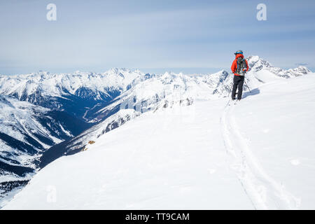 Skifahrer, die sich vom Gipfel des Youngs Peak im Glacier National Park, Kanada, nach dem Skifahren bis vom Parkplatz in Rogers Pass, der Morgen. T Stockfoto