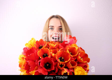 Porträt der jungen Frau mit schönen Blumenstrauß aus Tulpen auf Hintergrund Stockfoto