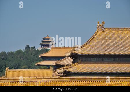 Chinesische Pagode auf einem bewaldeten Hügel; orange und gelbe Dächer der traditionellen Gebäuden Form der "Verbotenen Stadt" in Peking im Vordergrund. Stockfoto