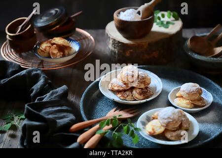 Poffertjes. Niederländische mini Pfannkuchen puffs mit Puderzucker serviert in mehreren kleinen Platten Stockfoto