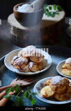 Poffertjes. Niederländische mini Pfannkuchen puffs mit Puderzucker serviert in mehreren kleinen Platten Stockfoto