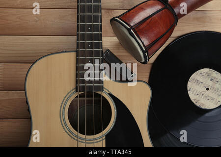 Gitarre mit Schallplatten und afrikanische Trommel auf holztisch Nahaufnahme Stockfoto