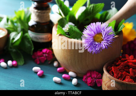 Kräuter, Beeren, Blumen und Pillen auf Farbe holztisch Hintergrund Stockfoto