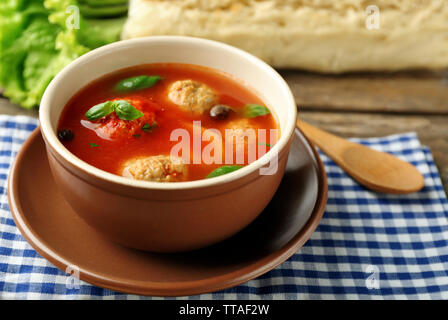 Tomatensuppe mit Fleisch Kugeln auf Löffel aus Holz auf Holz- Hintergrund Stockfoto