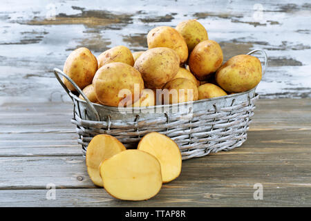 Junge Kartoffeln in Weidenkorb auf hölzernen Hintergrund Stockfoto