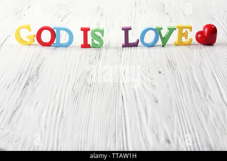 Gott ist die Liebe mit bunten Kunststoff Holz Buchstaben auf weißem Hintergrund dargestellt Stockfoto