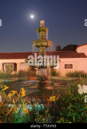 Lange Exposition der Verfassung Brunnen an der Mission San Gabriel Spielhaus mit der aufgehenden Vollmond im Hintergrund. Stockfoto