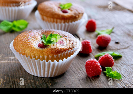 Leckere Muffins mit Beeren und frischer Minze auf holztisch Nahaufnahme Stockfoto