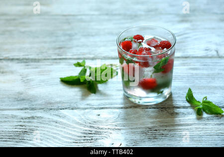 Glas kalten erfrischenden Sommerdrink mit Beeren und Eiswürfel auf Tisch Nahaufnahme Stockfoto