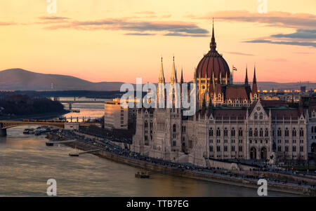 Stadtbild von Budapest mit hellen Parlament und Donau mit Brücke. Rosa und Lila Farben des Himmels spiegelt im Wasser während des Sonnenuntergangs. Stockfoto