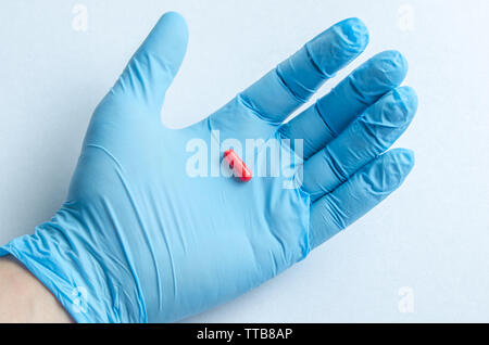 Die Hand des Health Care worker in Blau medizinische Handschuhe Holding eine Pille Stockfoto