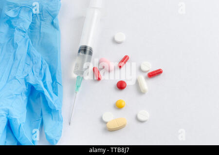 Blau medizinische Handschuhe, Spritzen und Pillen mit Pillen auf weißem Hintergrund Stockfoto