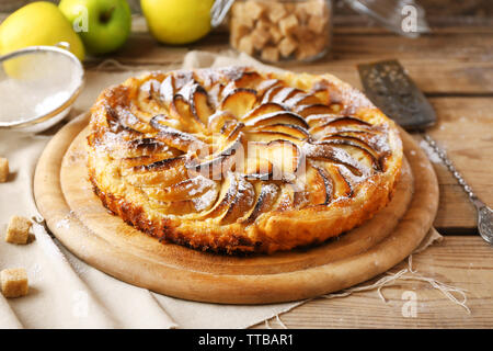 Hausgemachten Apfelkuchen auf Schneidebrett und frische Äpfel auf hölzernen Hintergrund Stockfoto