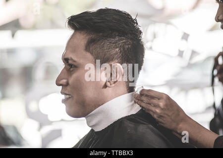 Seitenansicht Portrait von attraktiven asiatischen Mann in seinem Nacken, die von den weissen Nacken bedeckt und schwarzen Tuch bereit für die Rasur an Barbershop Stockfoto