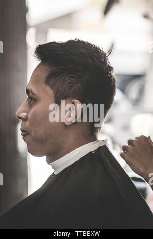 Seitenansicht Portrait von attraktiven asiatischen Mann in seinem Nacken, die von den weissen Nacken bedeckt und schwarzen Tuch bereit für die Rasur an Barbershop Stockfoto