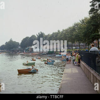 1960, historische, Sommer und Kinder in kleinen hölzernen Paddel Boote oder Tretboot auf dem See zum Bootfahren auf Roath Park, Cardiff, Wales. Ein beliebter Park, viktorianischen Design, das Land wurde die Stadt im Jahre 1887 vor allem gespendet vom Marquis von Bute und 1894 für die Öffentlichkeit geöffnet. Stockfoto