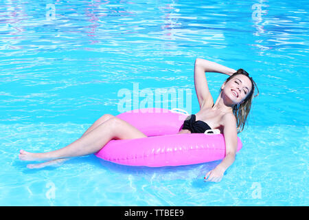 Junge Frau ruht auf rosa Gummiring im Pool Stockfoto