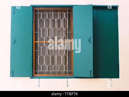 Open Green Holz- Fenster mit Fensterläden und Metall gerieben an der Wand. Stockfoto