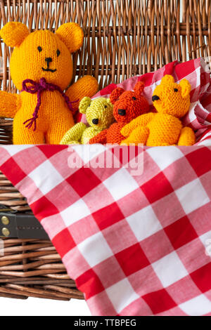 Gestrickter Teddybär Spielzeug auf kariertem Stoff Material in einer Rattan Picknickkorb. Teddybären Picknick Konzept Stockfoto