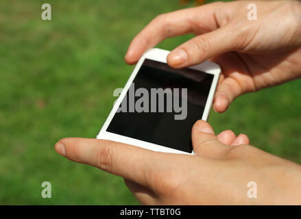 Weibliche Hände halten Smart Handy im Freien Stockfoto