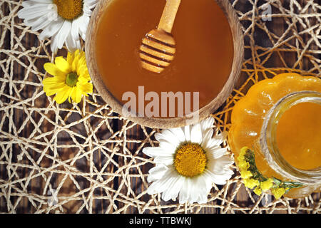 Honig im Topf und in der Schüssel, Pendelarm und Blumen auf wicker Mat closeup Stockfoto