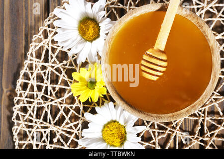 Honig im Topf und in der Schüssel, Pendelarm und Blumen auf wicker Matte auf Holz- Hintergrund Stockfoto
