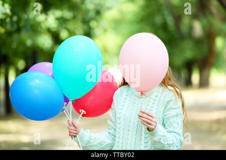 Mädchen mit Ballons versteckt sich hinter dem Ballon Stockfoto