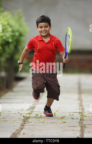 Junge läuft mit einem Tennisschläger Stockfoto