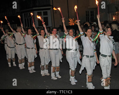 Honiton, Devon, England - 10. AUGUST 2012: eine Truppe von jungen Dame Morris Dancers halten ihre Fackeln hoch, da sie in der Nacht Zeit Stockfoto