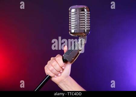 Weibliche hand mit einem retro Mikrofon gegen farbigen Hintergrund Stockfoto