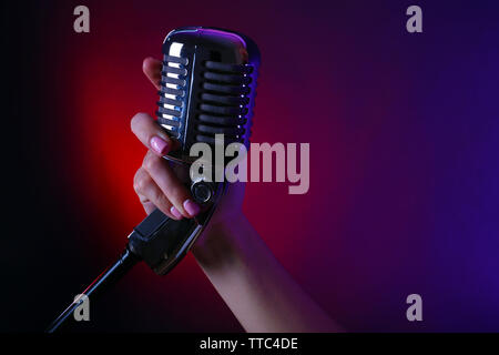 Weibliche hand mit einem retro Mikrofon gegen farbigen Hintergrund Stockfoto