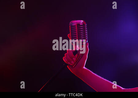 Weibliche hand mit einem retro Mikrofon gegen farbigen Hintergrund Stockfoto