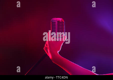 Weibliche hand mit einem retro Mikrofon gegen farbigen Hintergrund Stockfoto