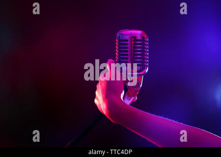 Weibliche hand mit einem retro Mikrofon gegen farbigen Hintergrund Stockfoto