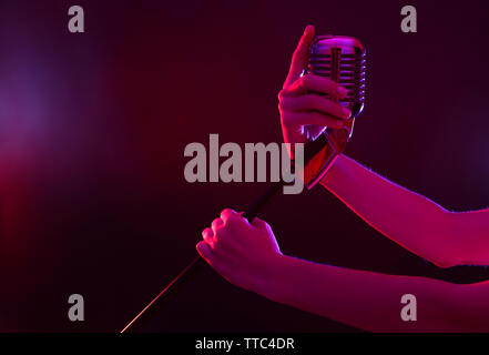 Weibliche hand mit einem retro Mikrofon gegen farbigen Hintergrund Stockfoto