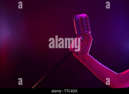 Weibliche hand mit einem retro Mikrofon gegen farbigen Hintergrund Stockfoto