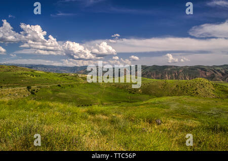 Blick auf die Autobahn mit drehen, um an die Garni Tempel in den Bergen von geghama Ridge in Armenien führenden gegen den blauen Himmel mit riesigen Clo abgedeckt Stockfoto