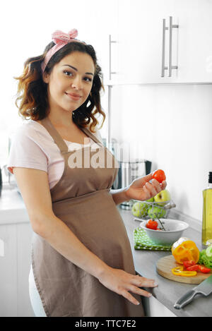 Süße schwangere Frau bereitet Vitamin-Salat auf die Küche Stockfoto